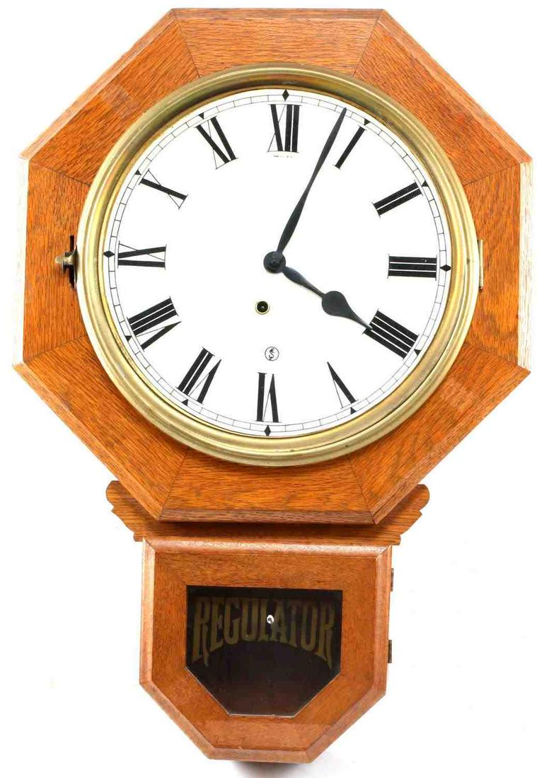 VINTAGE HANGING WOODEN WALL CLOCK E INGRAHAM CO.: E. Ingraham Co. label to back. Wall clock with roman numerals and hour and minute hands. Key inside bottom. Window at bottom marked Regulator. Untested. Measures 25 X 17.5 inches.