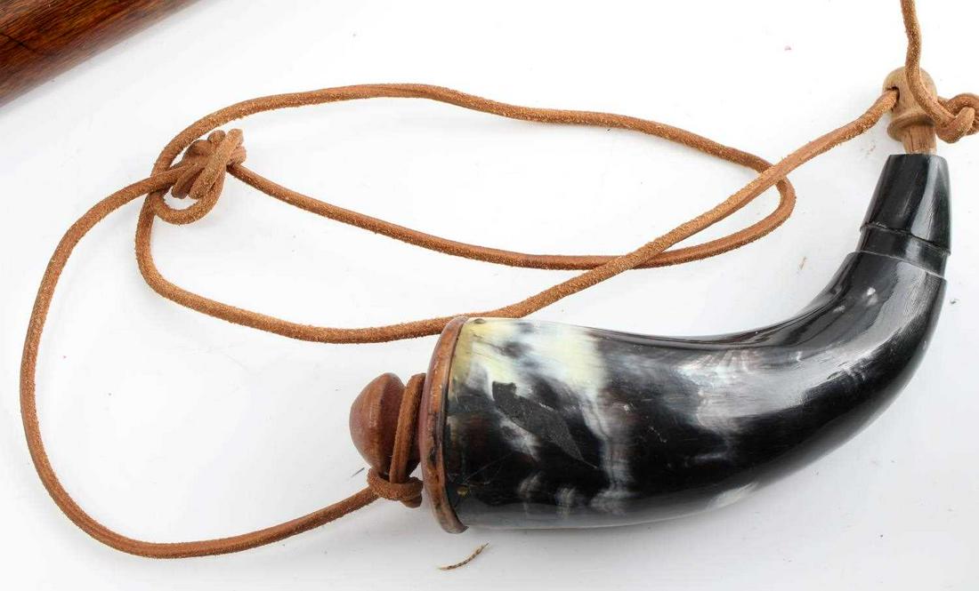 BLACK POWDER HORN W CLAY TOPPER & LEATHER STRAP: Black and tan coloration. In good condition with slight crack near top. Measures 10.5 inches.