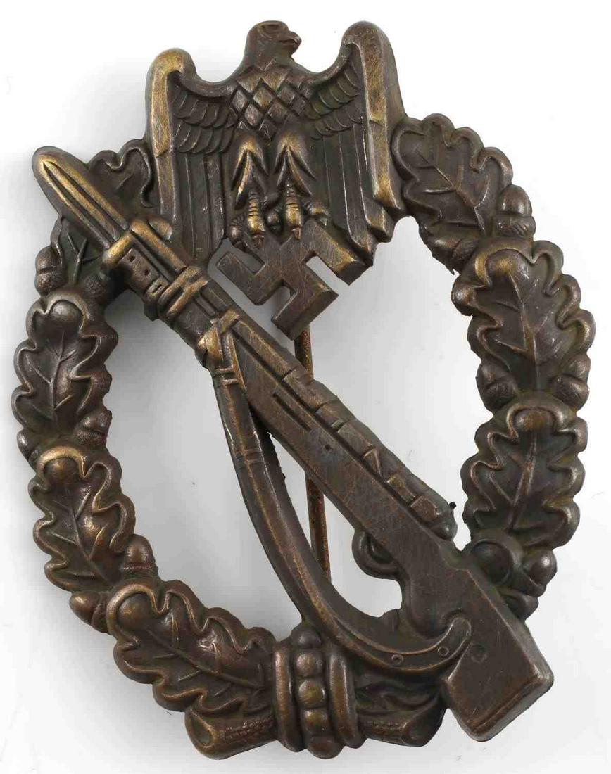WWII GERMAN BRONZE INFANTRY ASSAULT BADGE: WWII German Bronze Infantry Assault Badge. Front of the badge has a Mauser K-98 with an Eagle clutching a swastika at the top. Thin vertical pin back on the rear. Stamped bronze construction. Very goo