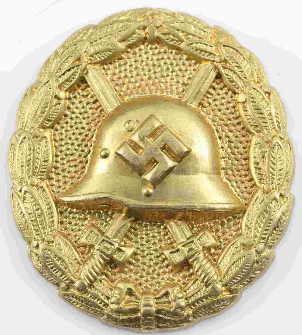 WWII GERMAN SPANISH CONDOR LEGION WOUND BADGE: German WWII Gold Spanish Condor Legion Wound Badge. The front shows a German helmet in the center with a pair of crossed swords in the back ground. All three are surrounded by an oval oak leaf wreath.