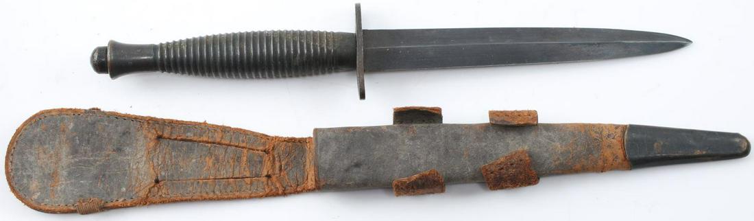 WWII BRITISH FAIRBARN SYKES COMBAT FIGHTING KNIFE: WWII British Fairbarn Sykes Combat Fighting Knife and Scabbard. Measures 10 7/8 overall. The double edged blade measures 7/8 wide and 6 inches long. The cross guard is marked England. The top pommel i