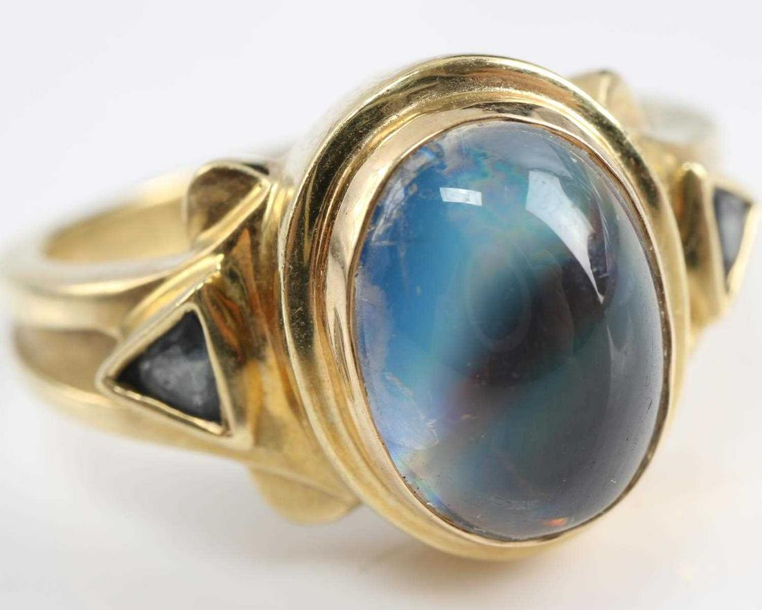 18K YELLOW GOLD & BLUE MOONSTONE WOMENS RING: Oval cut blue moonstone at center with triangular cut topaz accent on each side. Moonstone measures 10.5 mm by 7.5 mm. Approximately 2.75 carats. Size 8. Weighs 9.4 grams total. This lot has a reserve