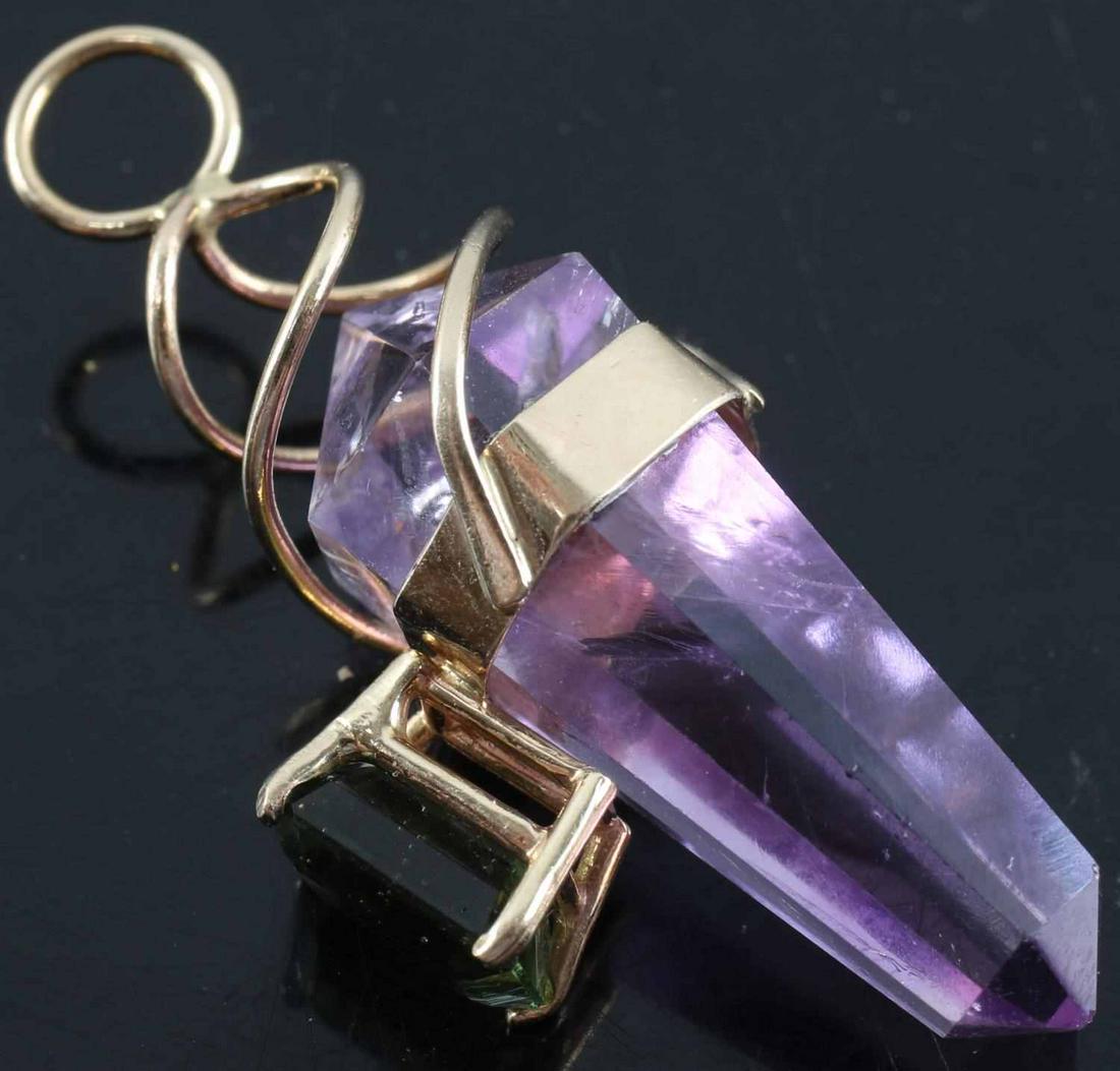 14K YELLOW GOLD AMETHYST & GREEN STONE PENDANT: Hexagonal obelisk pendant of amethyst with attached moss green stone. Likely moldavite or tourmaline. Spiral attachment of 14k gold. Measures 1.5 inches. Weighs 5.3 grams. This lot has a reserve.
