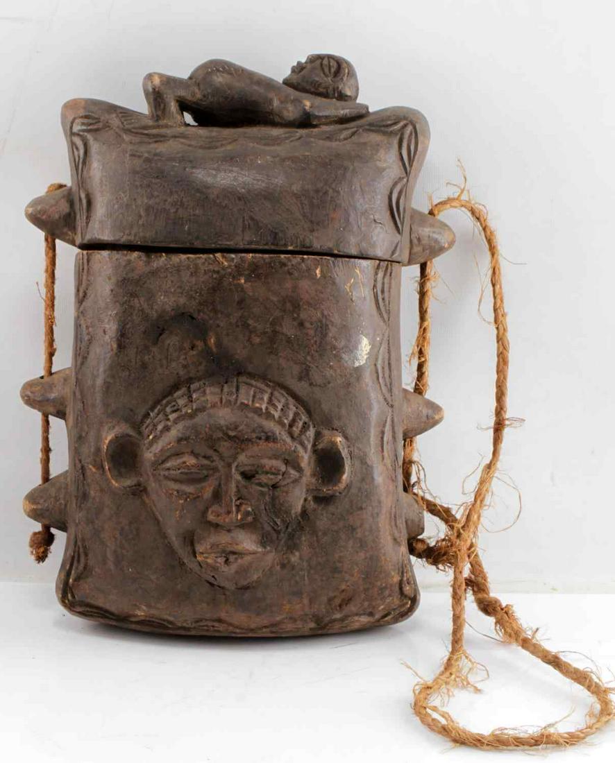 KUBA TRIBE TUKULA HAND CARVED PURSE BOX W RAFIA: Very nicely carved kuba box used to carry expensive tukula dye. Carved figure reclines on box lid and face is carved onto front. Rafia carrying strap. In very good condition. Measures 15 inches by 4.5