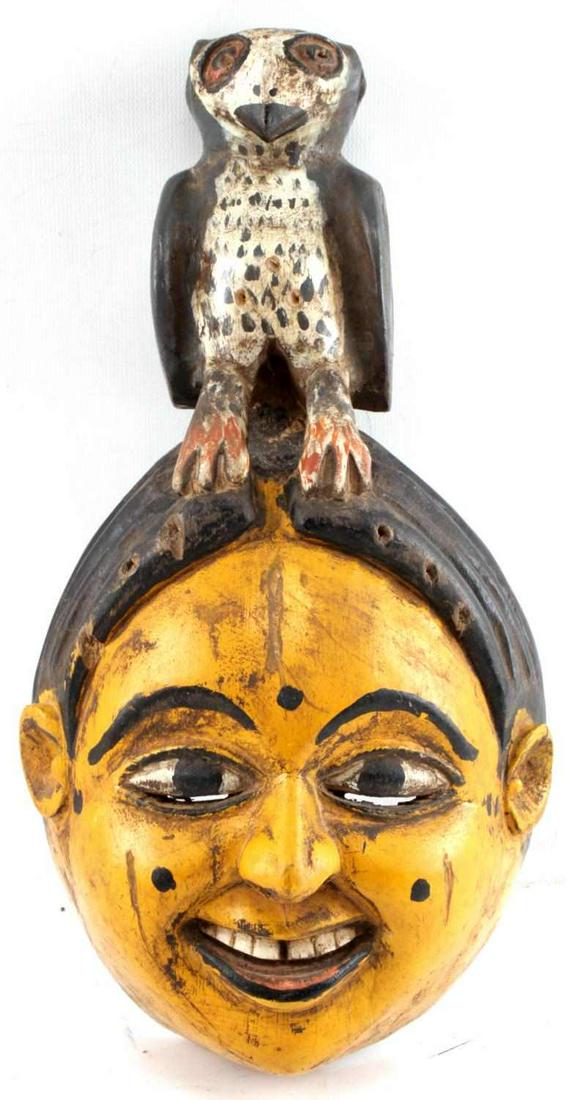 LOT OF TWO MASKS ANANG IBIBIO POLYCHROME PAINTED: One painted wood mask showing animal atop head. Measures 13 inches by 5.5 inches by 6.5 inches. One painted mask with kneeling woman holding onto two snakes. Measures 15 inches by 3 inches by 7 inches