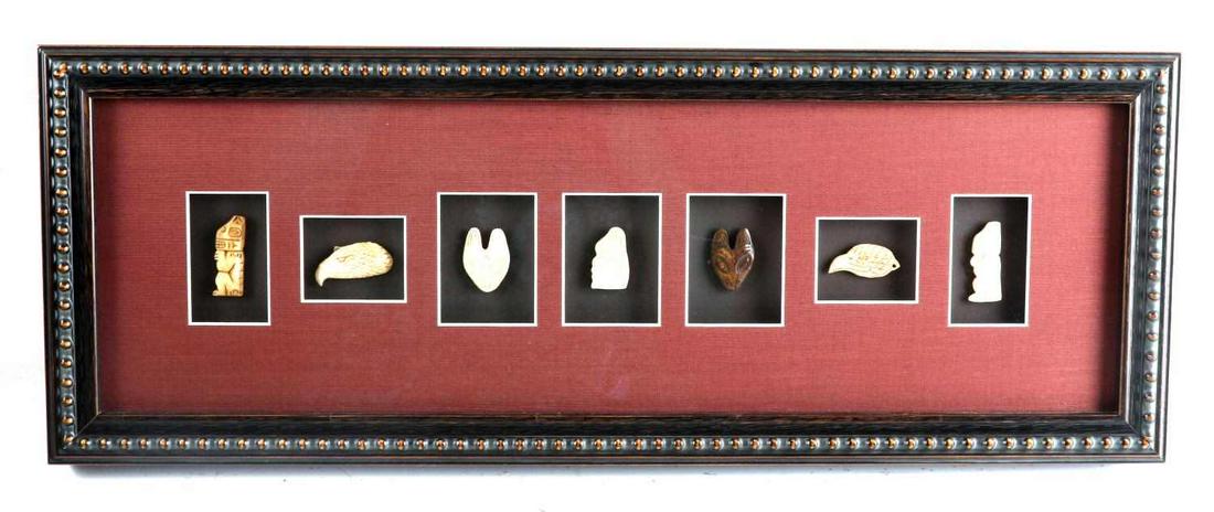 DISPLAY OF HAND CARVED PACIFIC NW BONE FETISH LOT: 7 hand carved bone fetishes in shadow box type frame. Eagle, bear mask, totem figures included. Measure about 1.5 inches each. Frame measures 24 X 9 inches. Hanger to back. Very good condition. This l