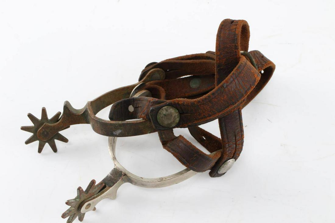 RICARDO METAL MANUFACTURERS PAIR OF SPURS: One pair of spurs from the Ricardo Metal Manufacturing Company with leather straps. Heel measures 3.5 inches. Spurs show signs of oxidation and straps show signs of use. The brand "Ricardo" is engrave