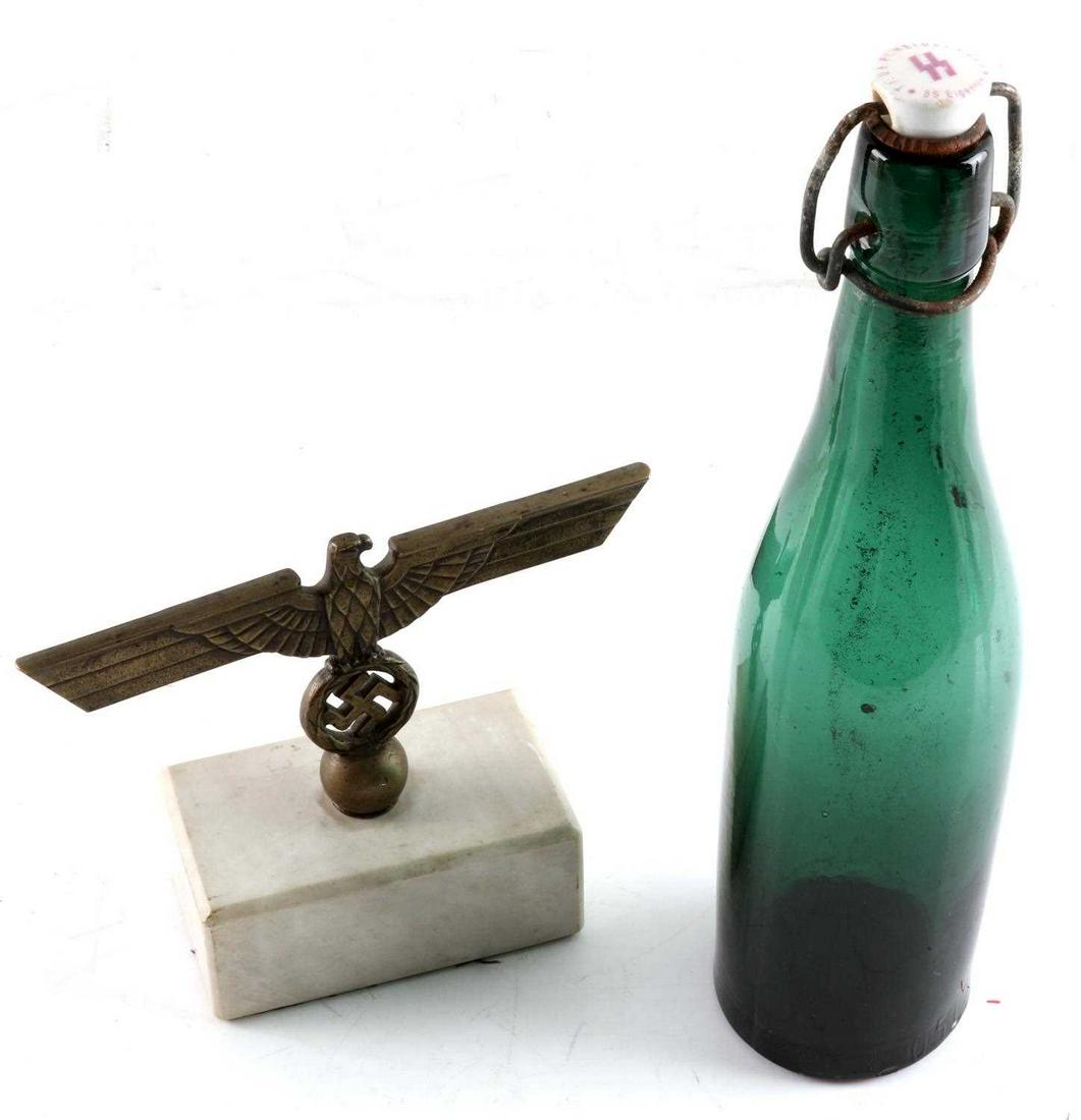 WWII THIRD REICH GERMAN REICHSADLER STAND & BOTTLE: Lot of two timepieces from Third Reich era: One green glass one liter beer bottle with glass cork stamped with the SS symbol and "Trub PL Heidelager SS Eigentom". (lees Polish from the storehouse, SS 