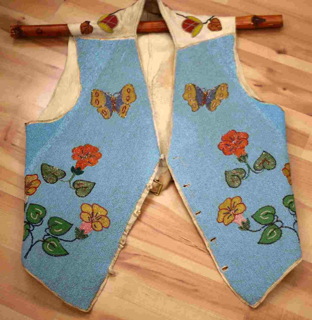19TH CENTURY CROW PLATEAU INDIAN BEADED HIDE VEST: thread and sinew-sewn soft hide; beaded on the front, back, and sleeves with a floral motif in colors of pea green, periwinkle, red, white, navy blue, greasy orange, and translucent green; hide shows 