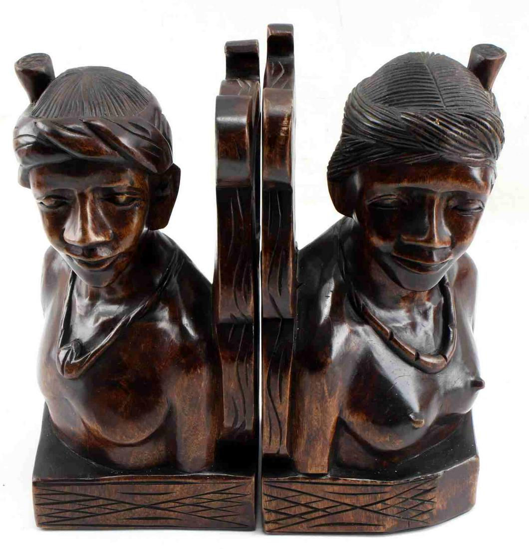 HAND CARVED SINGLE PIECE WOODEN BOOKENDS OCEANA: One pair of single piece, hand carved wooden bookends, perhaps mahogany, depicting a native man and woman from Oceana. Objects measure 11 inches by 6 inches and are in very good condition, with few we