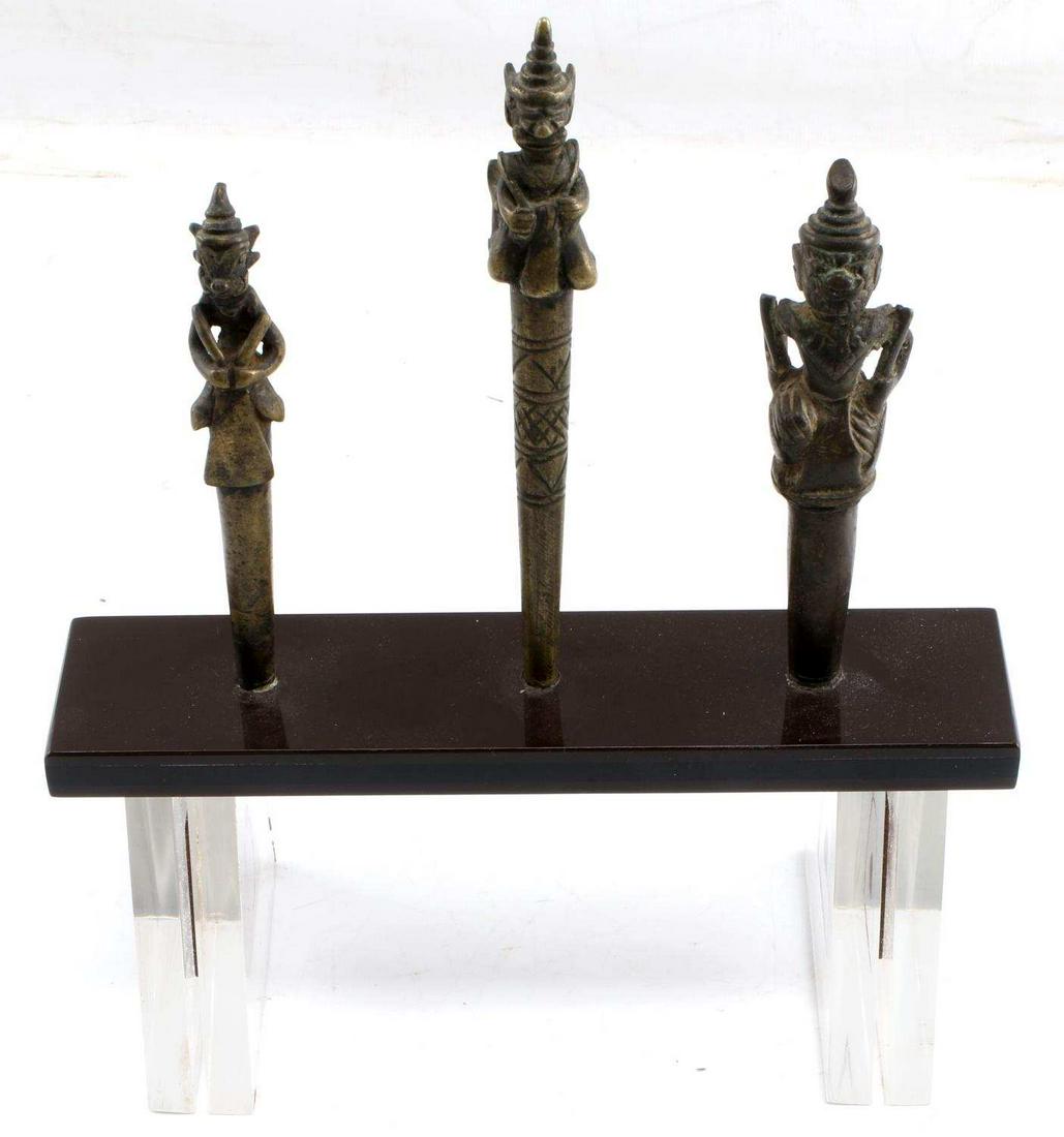 LOT OF THREE BRONZE BURMESE TATTOO NEEDLE TOPS: Antique top weights for tattooing needles with custom stand. Weights measure 5 inches to 6 inches. All in good condition. This lot has a reserve.