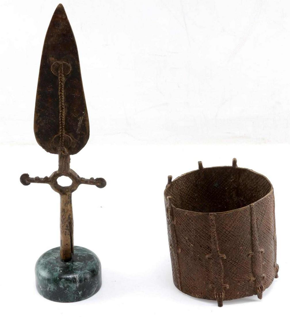 BRONZE ASHANTI CYLINDER CUFF & AFRICAN SPEAR: Possibly an arm cuff. Measures 4.75 inches by 4 inches. In good condition. African spear head on stand. Measures 10.75 inches (12 inches with stand) by 3.25 inches. This lot has a reserve.