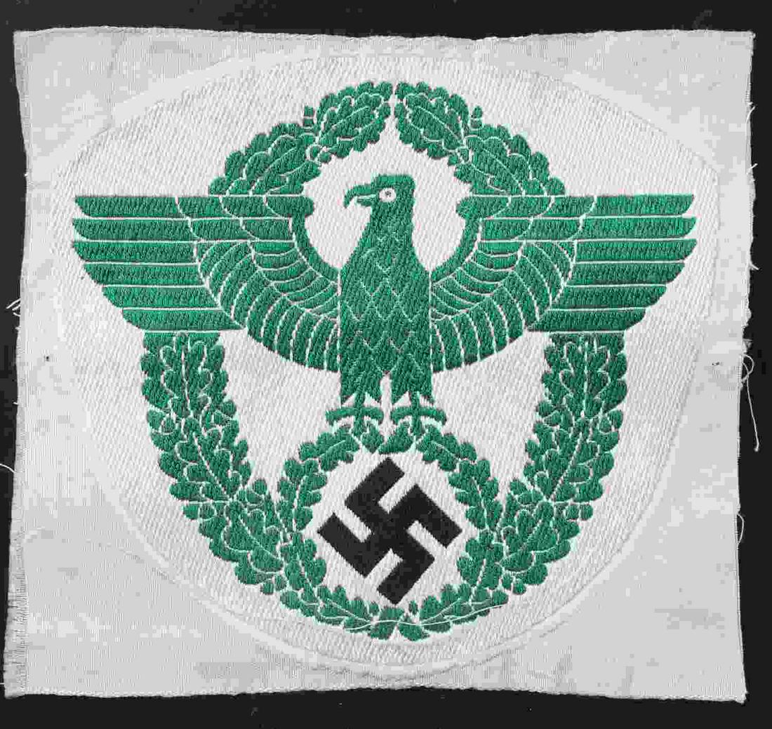 WWII GERMAN FIELD POLICE CLOTH ARM EAGLE PATCH: German WWII Field Police Cloth Arm Eagle. Measures 4 1/4" wide by 3 7/8” tall. The front shows a German eagle clutching a swastika in his talons surrounded by an oval oak leaf wreath. Machine embroi