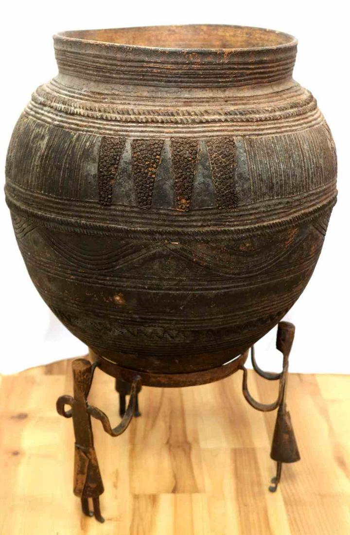 YORUBA NIGERIAN POTTERY EARTHENWARE VESSEL: West African, Nigerian, fine tooled earthenware pottery with figurative metal work stand. Height 22 inches with stand and a 14 inch diameter,