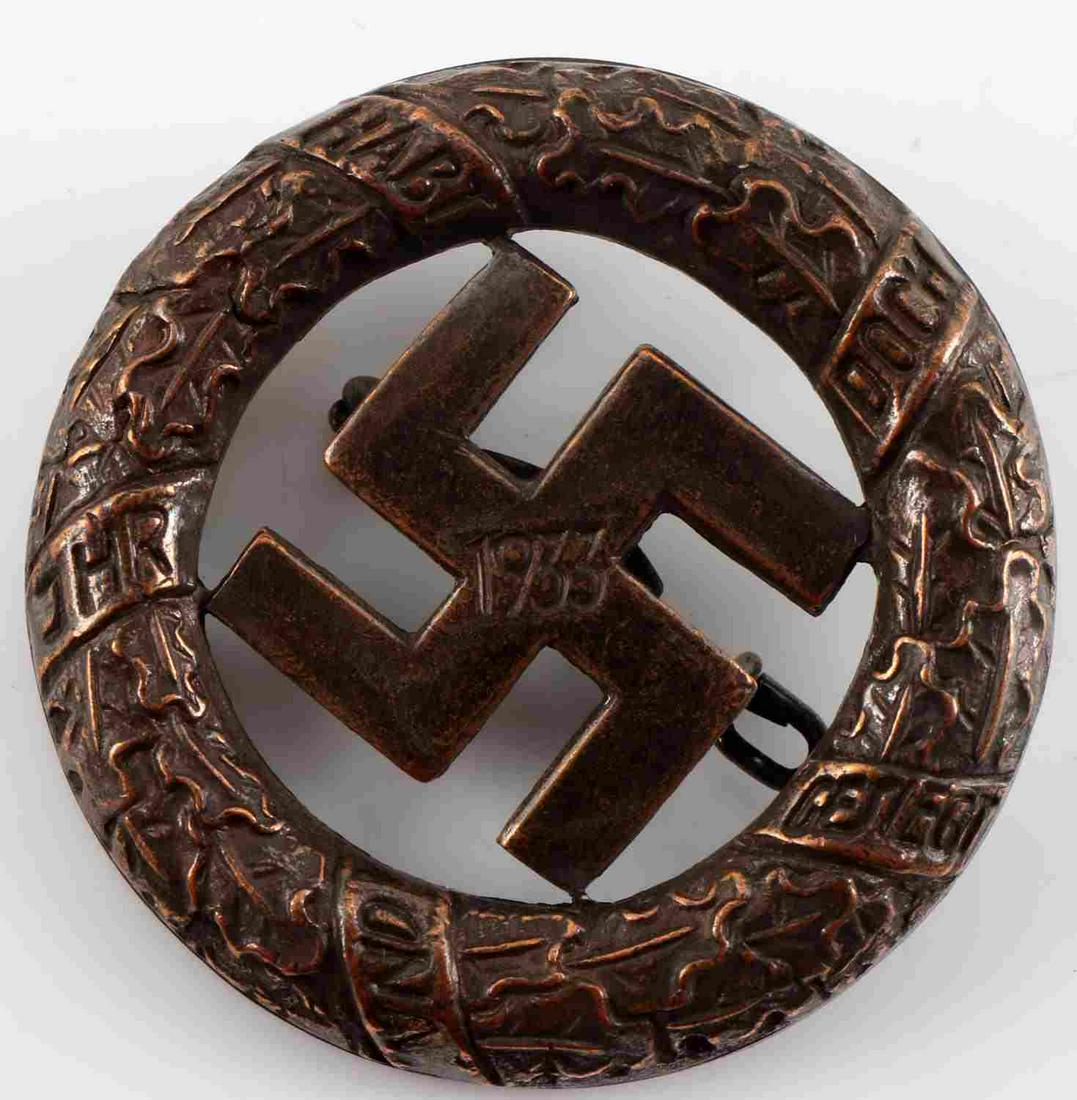 WWII GERMAN 1933 2ND ISSUE BLOOD ORDER GUA MUNCHEN: German WWII 2nd Issue 1933 Blood Order Gau Munchen Commemorative Decoration. Measures 1 3/8” in diameter. The front shows a swastika in the center dated ‘1933’ surrounded by a round oak leaf wre