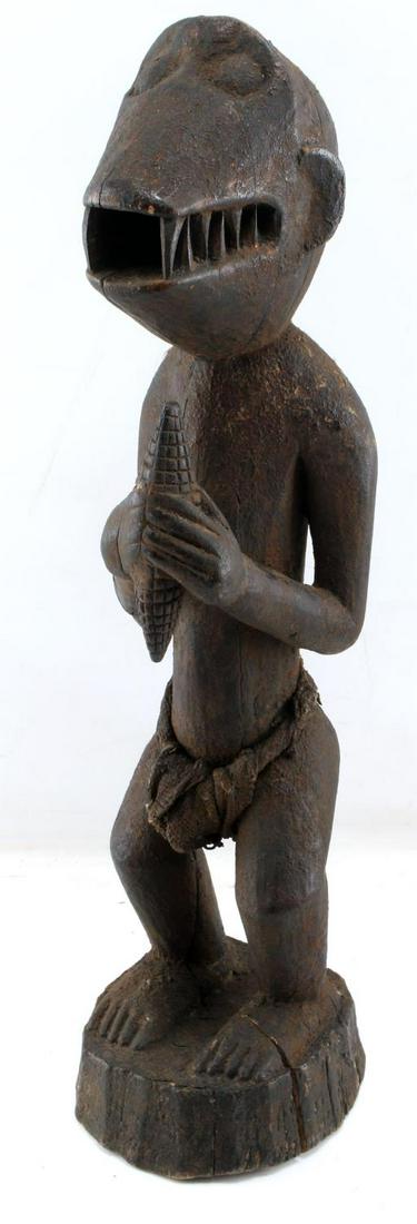 BAULE MONKEY GBERKE AFRICAN ZOOMORPHIC SCULPTURE: Tall carved wooden effigy of a classic Mbra Monkey statue, a Shrine sculpture that are also referred to as Gberke. This sculpture features the monkey with hands in gesture of offering with a piece of