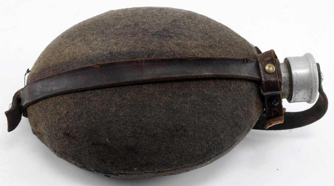 WWII GERMAN MILITARY WATER FLASK CANTEEN W COVER: Aluminum canteen with felt covering and leather strap. Measures about 8 inches long. Little wear, overall good condition. Unauthenticated, sold as is.