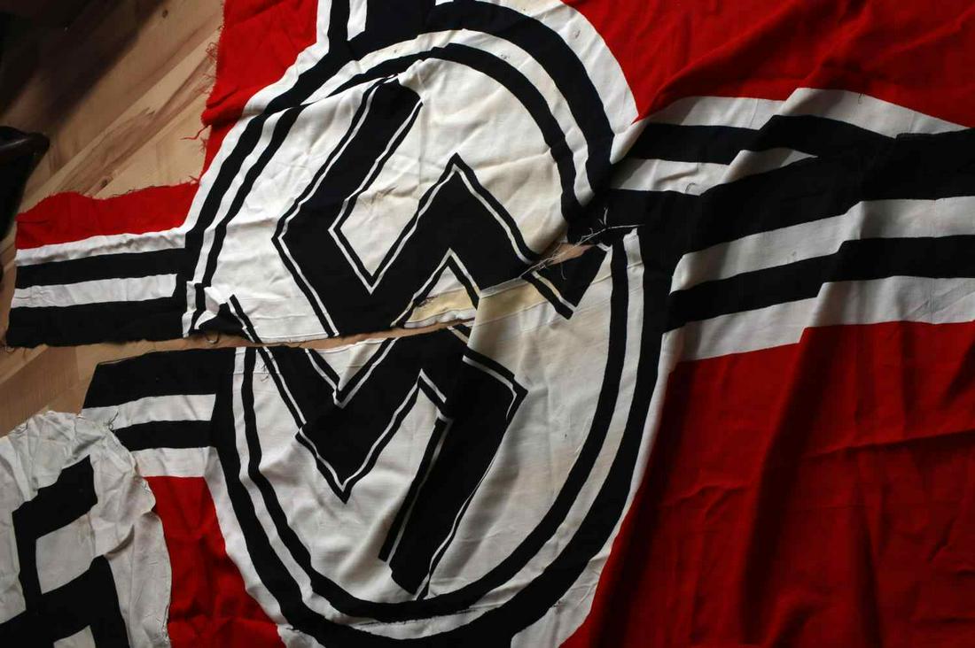 WWII THIRD REICH GERMAN KRIEGSFLAG SWASTIKA SYMBOL: WWII Third Reich German Kriegsmarine flag cut into two pieces measuring a total of 60 inches by 48 inches. This piece shows fraying and staining throughout. One circular Swastika symbol cut out from f