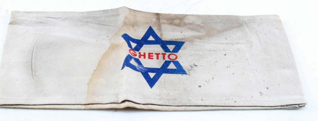 WWII GERMAN JEWISH STAR OF DAVID GHETTO ARM BAND: WWII German 3rd Reich Jewish Star of David Arm Band. Measures 4 inches by 9 inches sewn, with blue Star of David in center and red lettering. Slight discoloration, overall good condition. Unauthentica