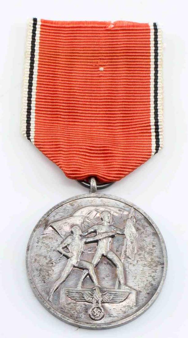 WW2 GERMAN 3RD REICH 1938 AUSTRIAN ANSCHLUSS MEDAL: WWII German Third Reich 1938 Austrian Anschluss Medal. Measures 1 1/4" in diameter. The front shows two men holding flags with a German eagle at the base. The reverse side reads ‘Ein Volk – Ein Re