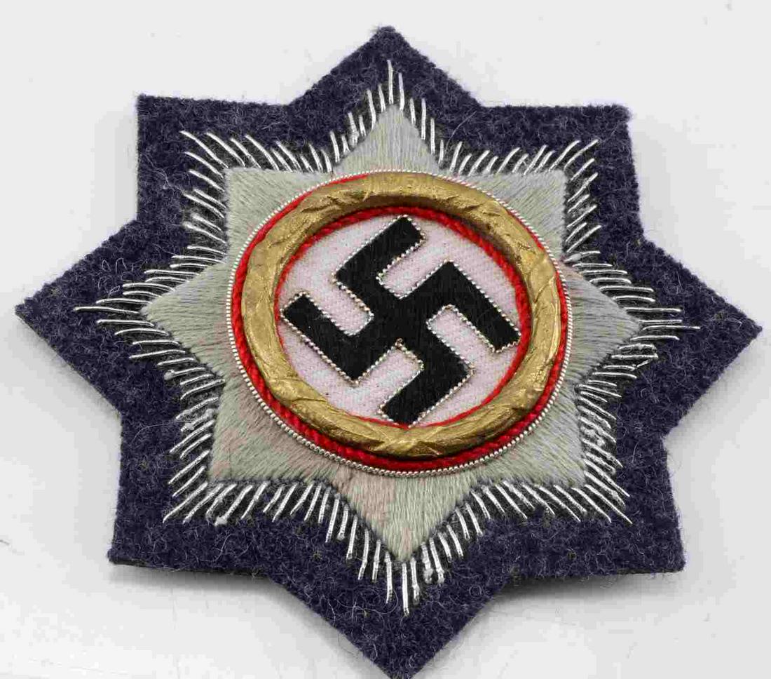 WWII GERMAN ARMY HEER CROSS IN GOLD PATCH: Grey and blue cloth with black swastika at center, gold metal wreath surrounding swastika, silver bullion sunburst design, and cloth backing. Measures 3.5 inches long. Very good condition. Unauthentic