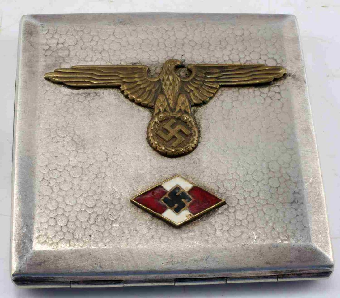 WWII GERMAN 3RD REICH NSDAP CIGARETTE CASE: WWIII German 3rd Reich NSDAP member cigarette case. Case is metal alloy construction, with metallic finish. Front features bronze toned imperial eagle insignia and white and red swastika emblem. Measu
