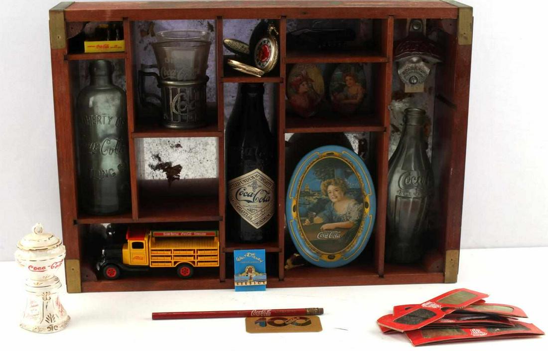 COCA COLA 100 CENTENNIAL CELEBRATION DISPLAY CASE: Coca Cola 100 Year Centennial Celebration Display Case. The case contains Coca Cola memmorabilia such as a pocket knife, pocket watch, 1900 stopper bottle, 1913 prototype bottle, pocket mirrors and a