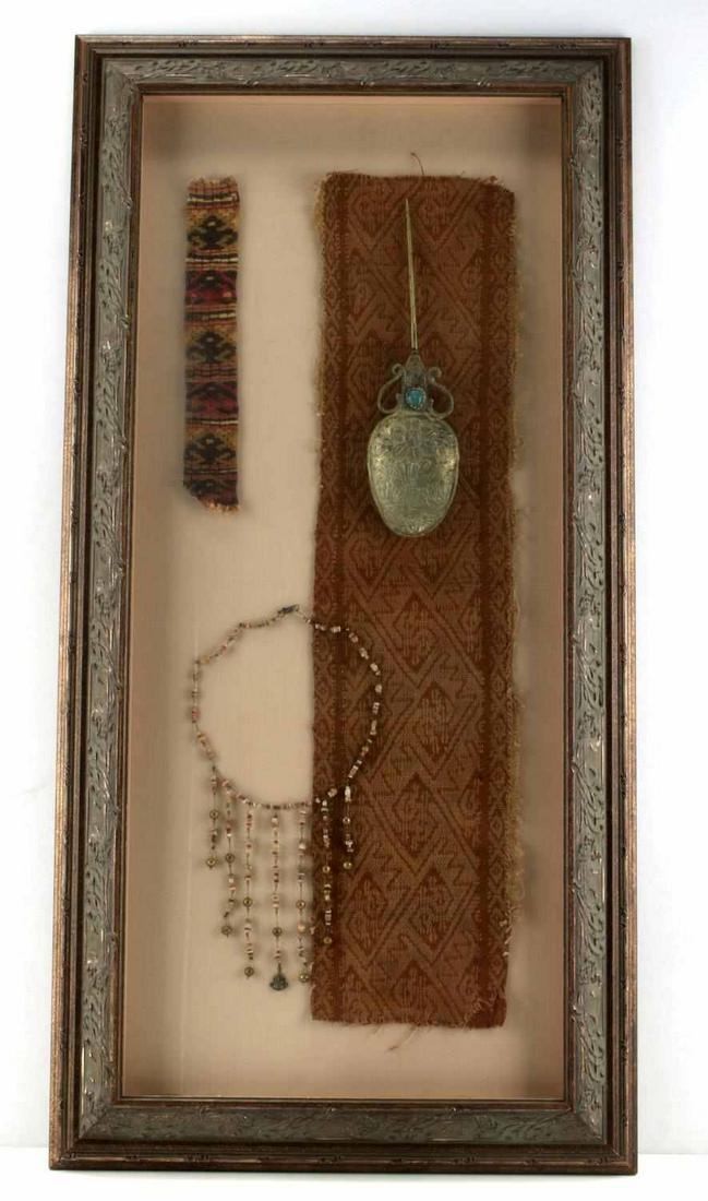 ANTIQUE BOLIVIAN TUPO SHAW PIN & TEXTILE DISPLAY: Antique silver shawl pin (10.5 inches) with blue cabochon possibly Chrysocolla and a tooled double headed turkey design, two textile pieces, and a bead necklace. Very good condition. Frame measures 35