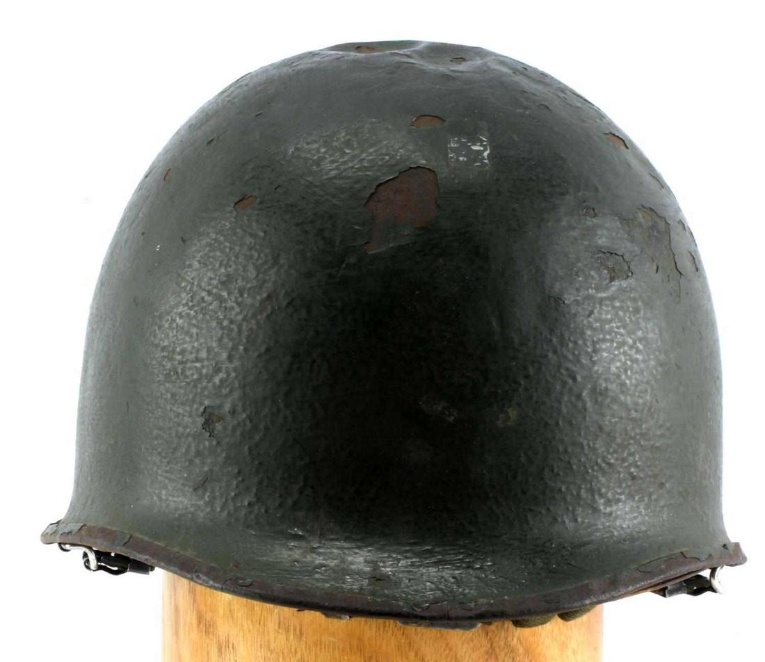 WWII & KOREAN WAR ERA US M1 HELMET W LINER: Green steel helmet with fold-over rim, swivel bales (1943), green liner, leather covered sweatband and canvas straps. Anchor symbol marked to metal closure clasp (Korean War period). Finish loss and s