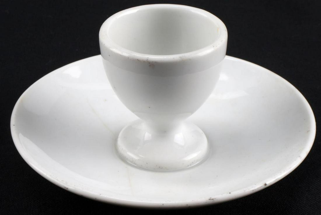 WWII GERMAN 3RD REICH PORCELAIN EGG CUP AND SAUCER: WWII German Third Reich Porcelain egg cup and saucer. Measure 5 inches wide and 2.5 inches tall. Bottom of dish features Reichsadler and makers mark "Puls" with the year 1941. Overall, good condition.