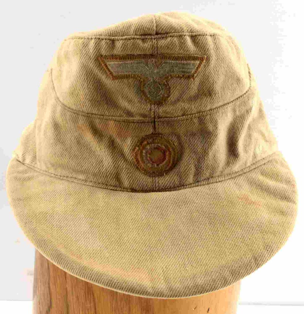 WWII GERMAN THIRD REICH AFRIKA KORPS M43 HAT: WWII German Afrika Corps M43 Cap. Tan with red interior cloth lining. Reichsadler eagle and Nazi party insignia on the front are stitched in and faded with age. Does not fluoresce. Some stitches are f