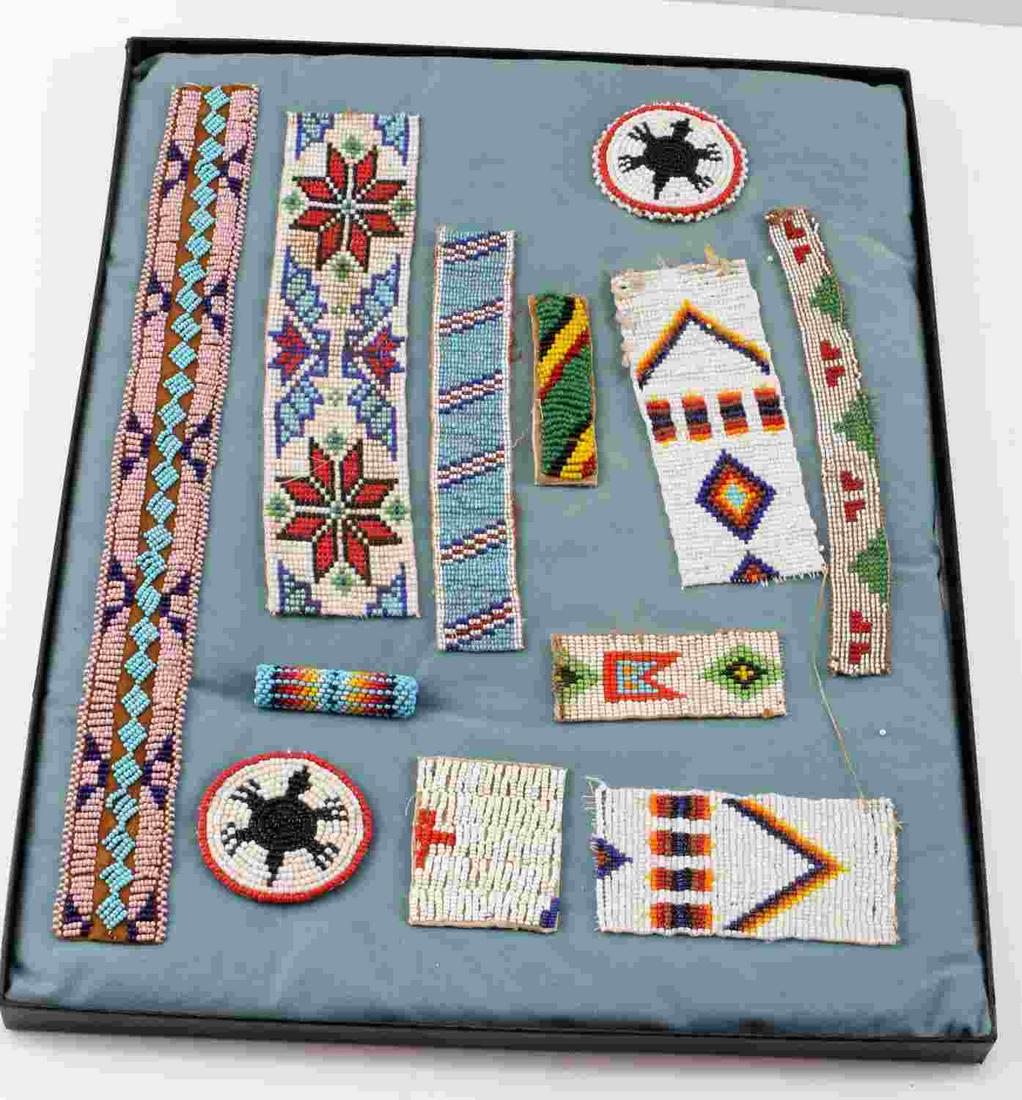 AMERICAN INDIAN BEADED PANELS ROSETTES COLLECTION: Riker box display of 12 American Indian beaded strips, panels and two beaded rosettes. Various ages and tribes including Seneca, Sioux, Cheyenne, Blackfoot and Apache.