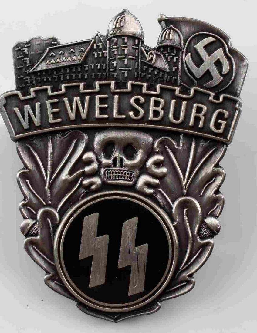 GERMAN WWII WAFFEN SS WEWELSBURG SKULL BADGE: Front reads "Wewwlsburg" and shows a castle scene at top with skull placed center. There is a pair of Waffen SS runics at the base. Has a clutch back post and brass brad on the reverse side. One piece