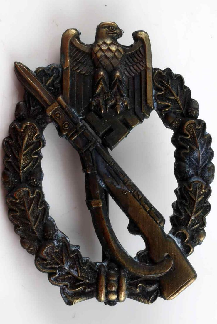 GERMAN WWII ARMY BRONZE INFANTRY ASSAULT BADGE: The front shows a Mauser K-98 rifle in the center with a German Army eagle at the top. Both are surrounded by an oval oak leaf wreath. Has a thin vertical pin back with a ‘c’ catch. The fittings a