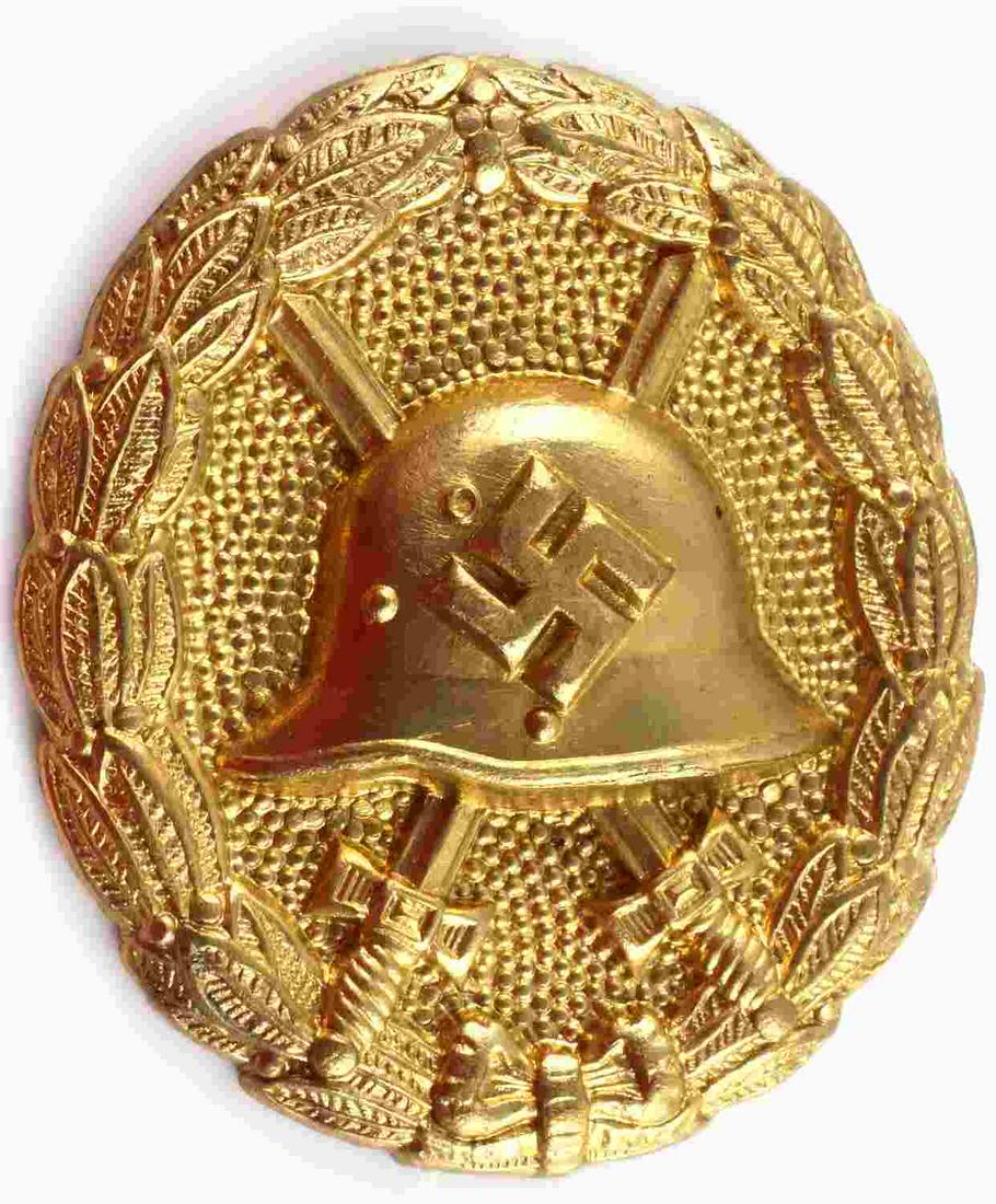 WWII GERMAN GOLD CONDOR LEGION WOUND BADGE: WWII German Gold Condor Legion Wound Badge. The front shows a German helmet in the center with a pair of crossed swords in the back ground. All three are surrounded by an oval oak leaf wreath. The pin