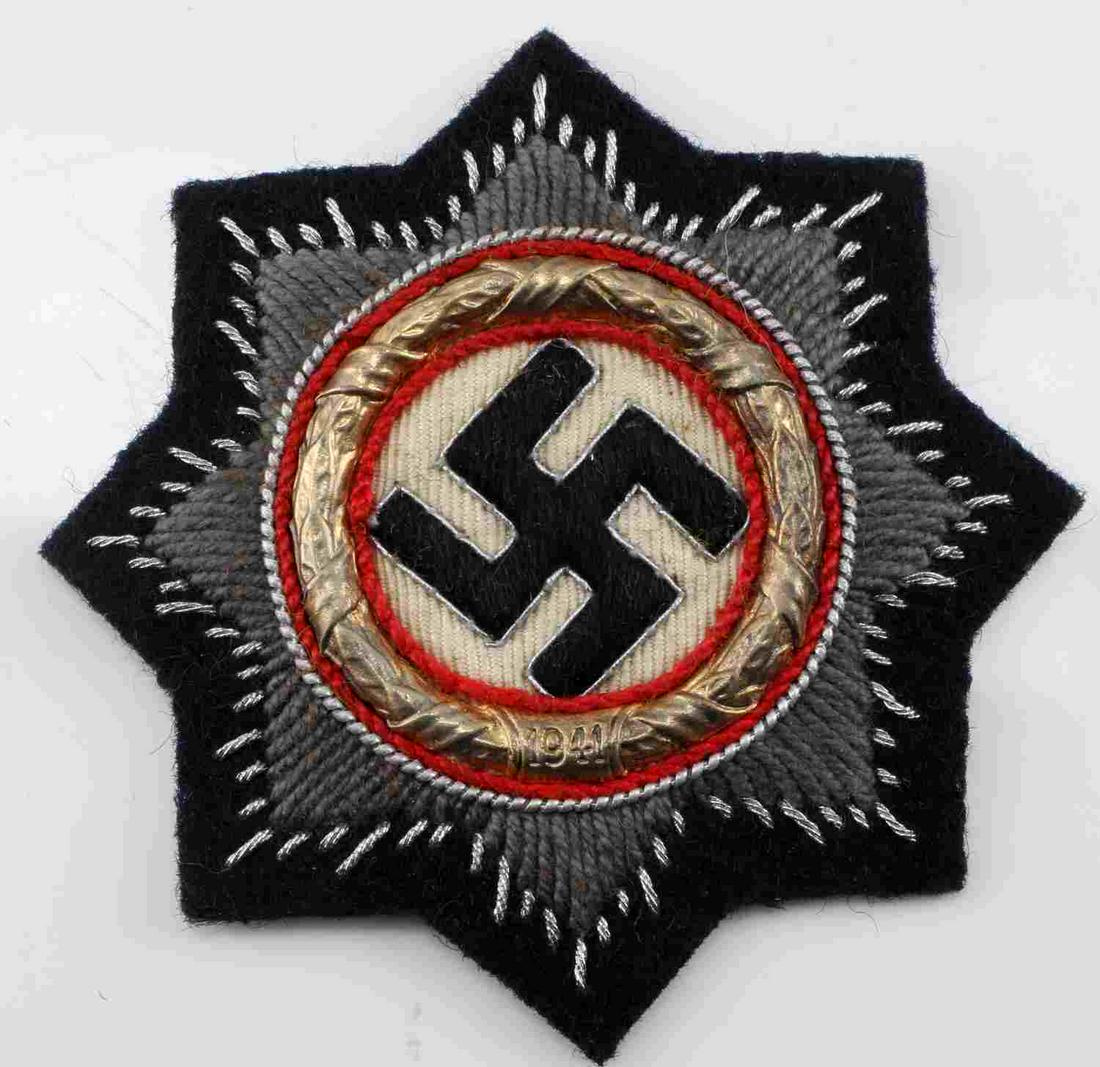 GERMAN WWII ARMY SS PANZER GERMAN CROSS: Measures 3 1/16” in diameter. The front shows a swastika in the center surrounded by a round brass oak leaf wreath dated ‘1941’ at the base. There are eight rays in the back ground. Has a paper 