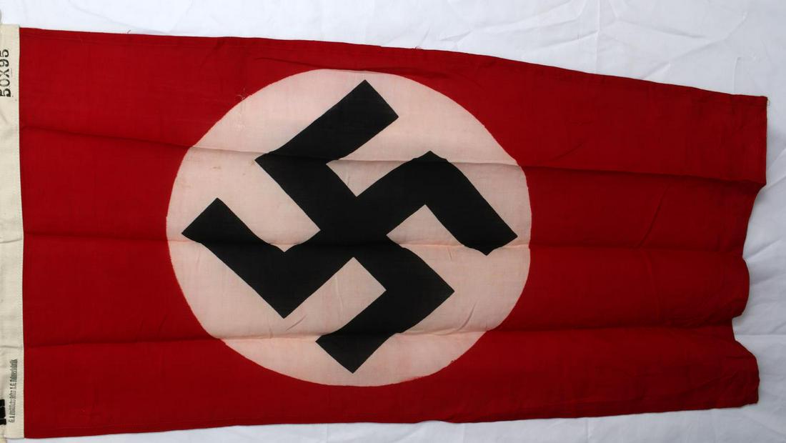 WWII GERMAN POLITICAL NSDAP SWASTIKA BANNER FLAG: WWII German Political NSDAP Swastika Banner Flag. Measures 38 1/4" wide by 20 1/4" tall. Shows a swastika in the center of the flag. Has a white cotton bunting with rope on one end. It is maker marked