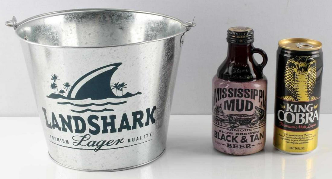VINTAGE BEER BOTTLE & CAN DECORATIONS LOT: Lot includes Vintage King Cobra malt liquor can, pull tab is unopened, bottom is punctured; also includes Mississippi Mud Beer Bottle; and also includes a "LANDSHARK LAGER" ice bucket. No liquid insid
