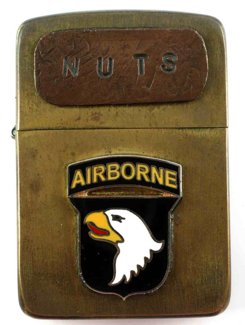 WWII KOREA 101ST AIRBORNE DIVISION ZIPPO LIGHTER: 'Nuts' on label to front and Airborne shield affixed to front as well, measures 2.25 inches tall, maker marked at bottom. Very good condition. First edition 1933 to 1954 block Zippo.