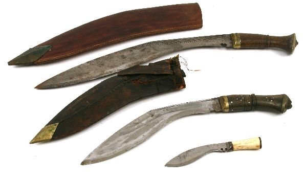 GURKHA KUKRI LOT OF 3: To include; 15 inch blade, wood grip, brass hilt, contained in its leather sheath; 11 inch blade, wood grip, brass hilt with lion head pommel, leather sheath with twin small knives (both with worm). A