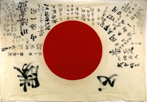 WWII JAPANESE "MEATBALL" FLAG: 41 x 58 inch cotton flag with painted Japanese script and symbols. Added corner ties (modern). Some staining and ink run, generally very good.