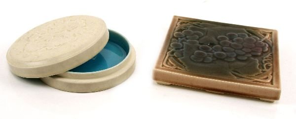 2 LOT ROOKWOOD POTTERY TRIVET AND COVERED DISH: Mint condition trivet #1683 with purple grape motif, measuring 5.75 inches square. Second item is mint condition powder cake dish with lid marked with "XXIV" (1924) and "2654" matt finish, white glaze