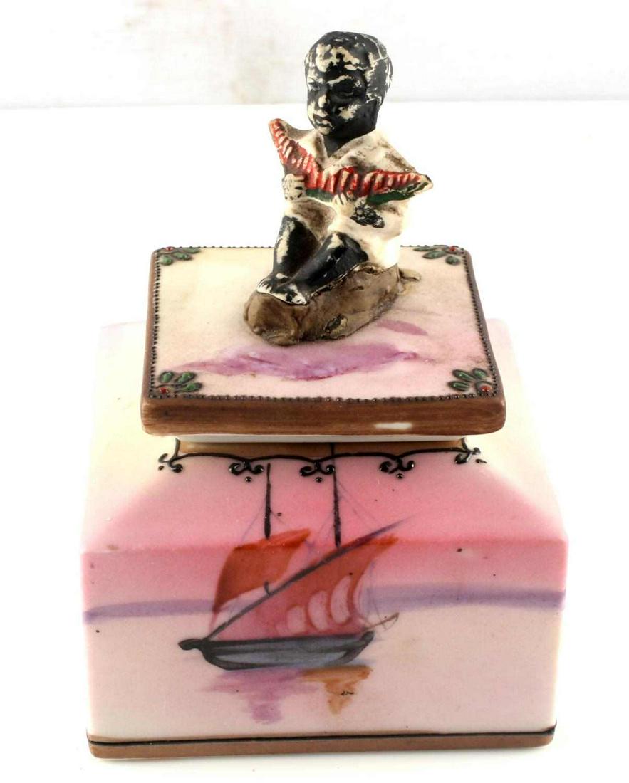 NIPPON CHINA BLACK AMERICANA PORCELAIN INKWELL: Made in early 1900's. Sailboat painted to bottom piece, light pink and purple colors, child figure with watermelon slice at top. Small 1.25 inch deep insert. Chips at rim of opening on bottom piece. S