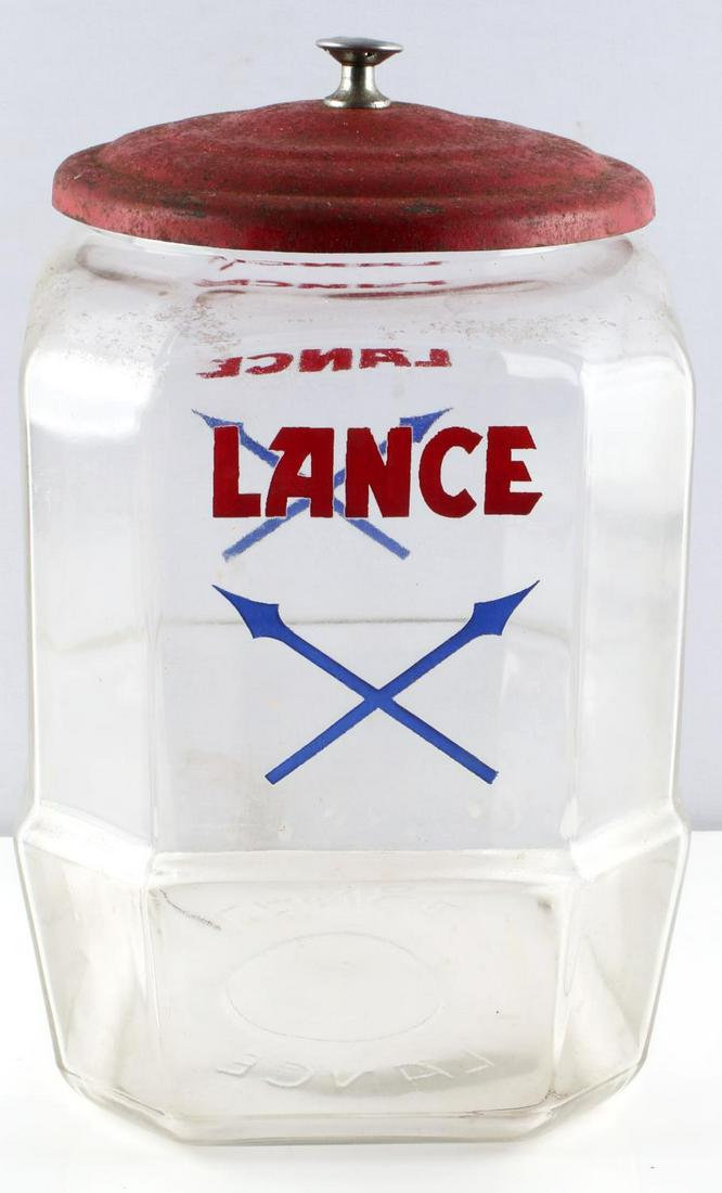 VINTAGE GLASS LANCE COOKIE OR CRACKER DISPLAY JAR: Vintage "Lance" Glass Cookie or Cracker Display Jar. Classic Lance logo with crossed arrows beneath it. Measures approximately 10.5 inches tall. Good condition, no chips or cracks present. Lid has som