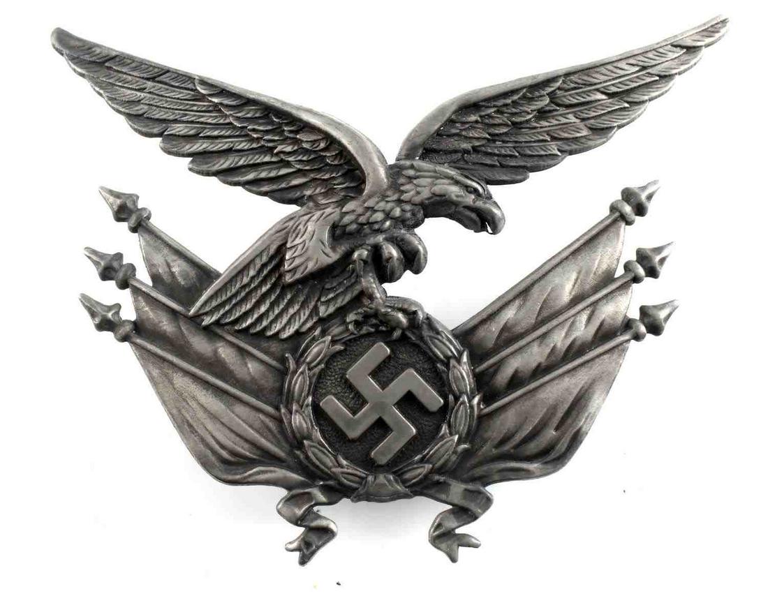 WWII GERMAN LUFTWAFFE GORGET CENTER EAGLE: WWII German Reichsadler and flag emblem off of a Luftwaffe standard bearer's gorget. 4 inches wide by 2 1/2 inches tall. One piece stamped nickel construction. Good condition. This lot has a reserve.