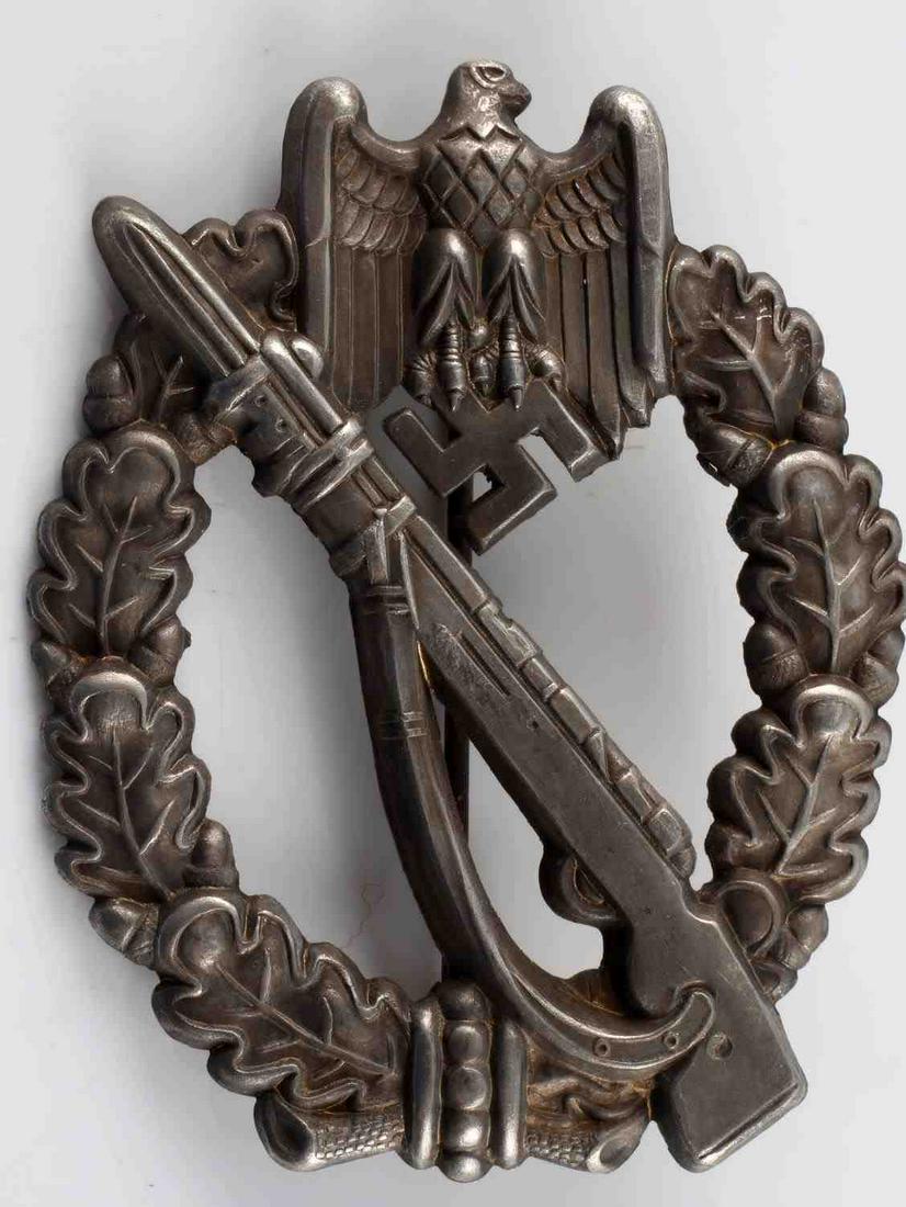 GERMAN WWII ARMY SILVER INFANTRY ASSAULT BADGE: The front shows a Mauser K 98 rifle in the center with a German eagle clutching a swastika in his talons at the top. Both are surrounded by an oval oak leaf wreath. Has a thin vertical pin back with a