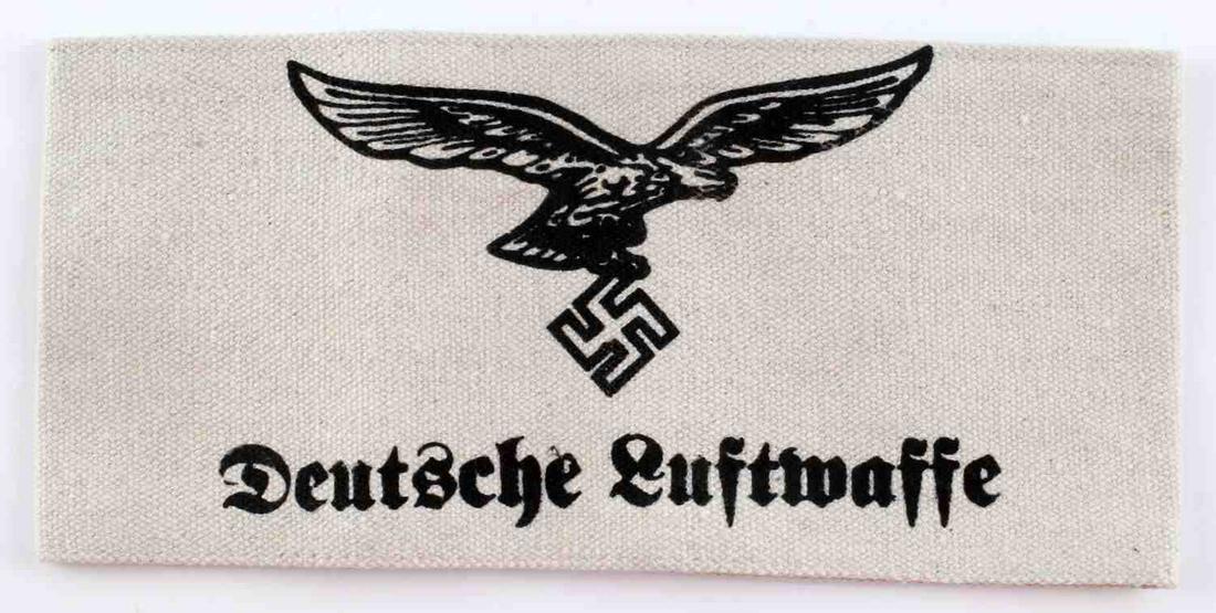 GERMAN WWII DEUTSCHE LUFTWAFFE EAGLE ARM BAND: Measures 8 1/8” wide by 3 3/4" tall. The front reads ‘Deutsche Luftwaffe’. It shows a German WWII Luftwaffe flying eagle clutching a swastika in his talons. One piece machine sewn printed white 