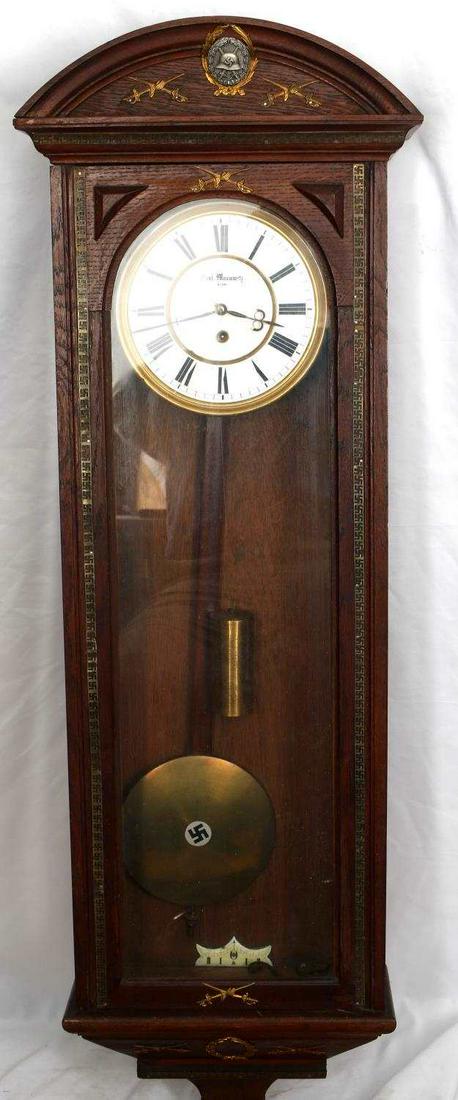 WWII GERMAN KARL MORAWITZ SWASTIKA ADORNED CLOCK: Interesting concoction. silver wound badge at tom, gloved gauntlet crossed swords throughout, swastika trim in brass top and sides, 34 by 15 by 6 inches, we were unable to start but should work.