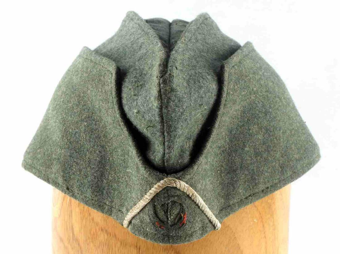 WWII GERMAN ARMY INFANTRY NCO OVERSEAS CAP: WWII German Army Infantry NCO Overseas Cap. 11 7/8 X 4 1/2 inches. Body is OD green wool. Braided flat silver bullion wire and cotton soutach inverted ‘V’ on the front. Grey satin lining on the in