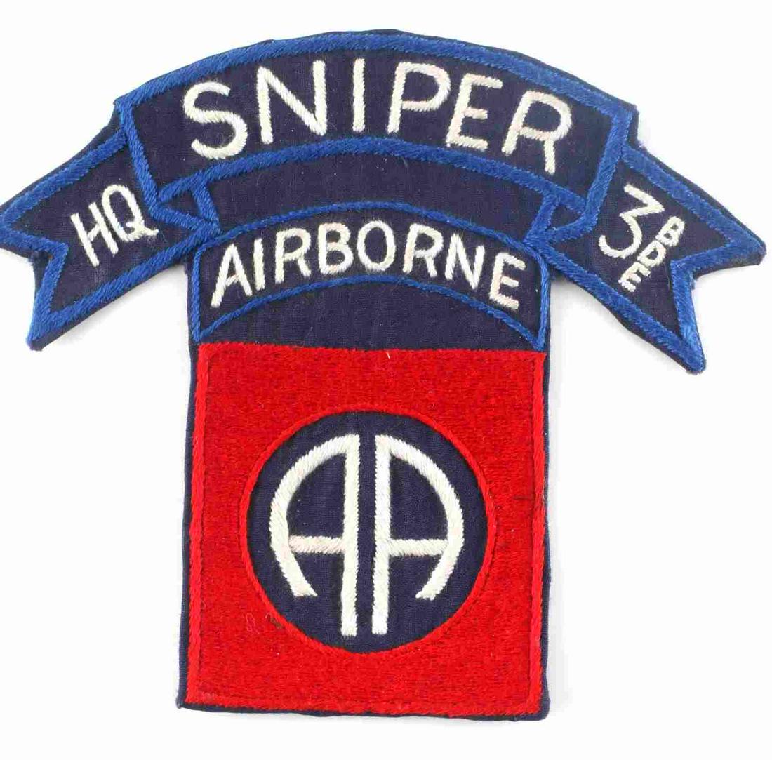 VIETNAM US ARMY 82ND AIRBORNE HQ SNIPER PATCH: US Vietnam Army 82nd Airborne HQ SNIPER Patch. Measures 5 1/16” wide by 4 3/8” tall. The front reads ‘SNIPER HQ 3 BDE Airborne AA’. There is Vietnamese newspaper on the reverse side. Machine e